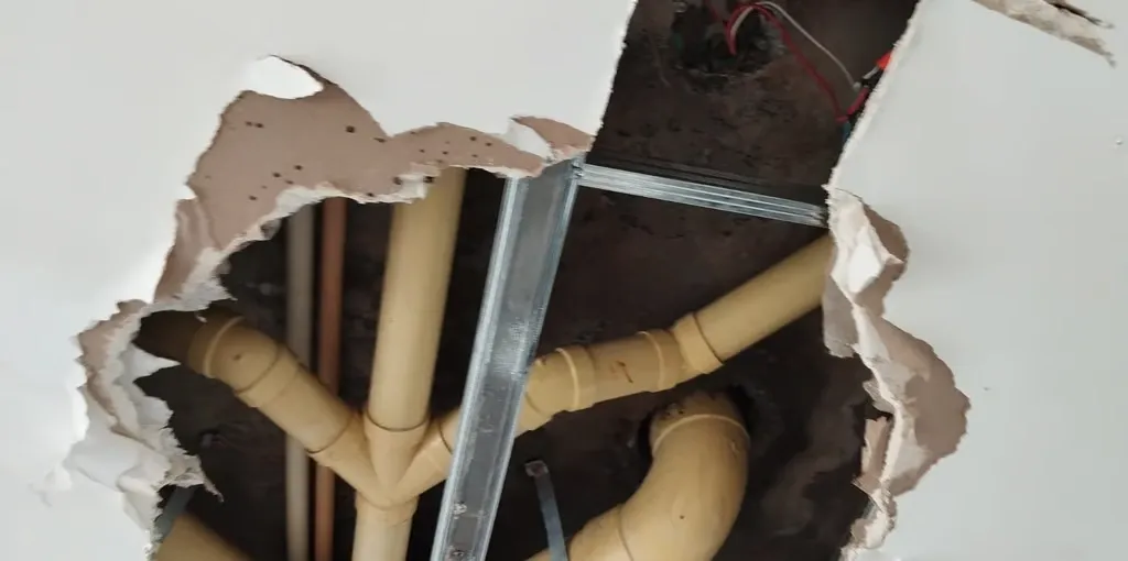 Pared abierta en la que se ven las tuberías de la red hidráulica